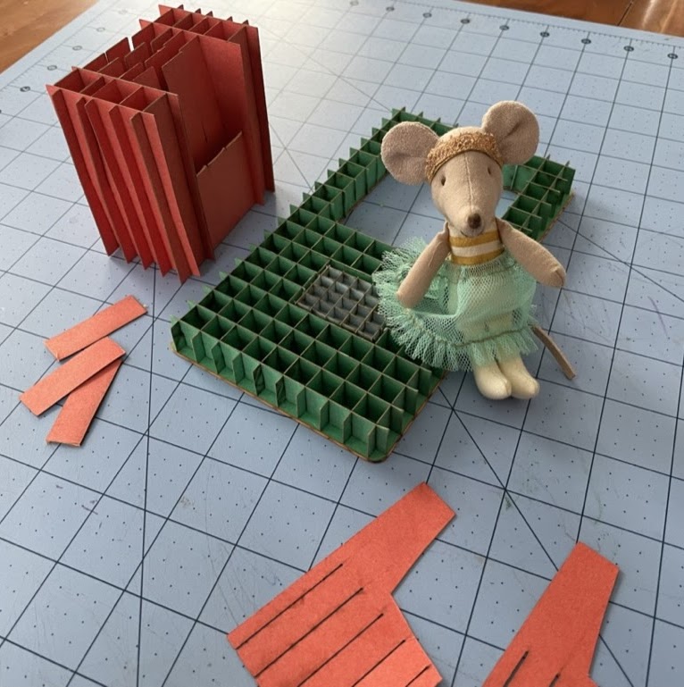 Torsion box structures made from paper strips, with a small mouse figure for scale